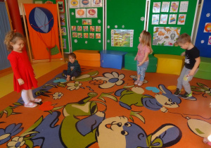 Dzieci na umówiony sygnał zatrzymują się przy sercach rozłożonych na dywanie.